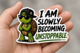 I Am Slowly Becoming Unstoppable Sticker | Funny Turtle Sticker | Motivational Decal — real sticker held in hand